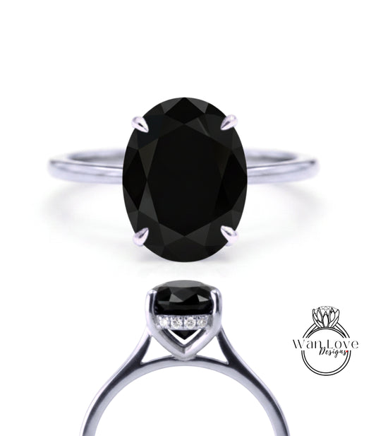 A close-up view of a silver ring with a large oval-shaped black gemstone, showcasing the intricate design and craftsmanship of the piece.