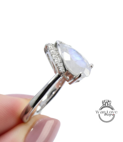 A close-up image of a person's hand holding a silver ring with a large, clear gemstone, likely a diamond, on the ring finger.