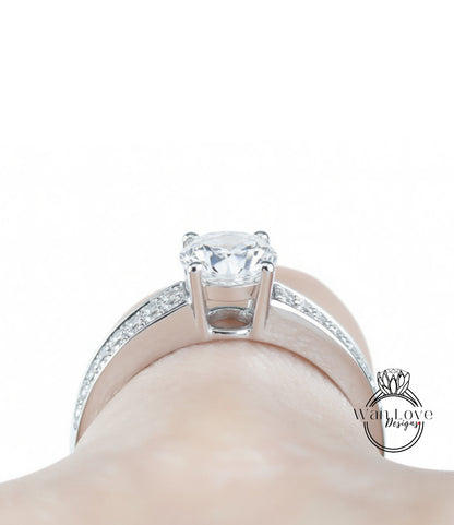 A close-up view of a diamond engagement ring on a person's hand, showcasing the sparkling center stone surrounded by a halo of smaller diamonds set in a silver band.