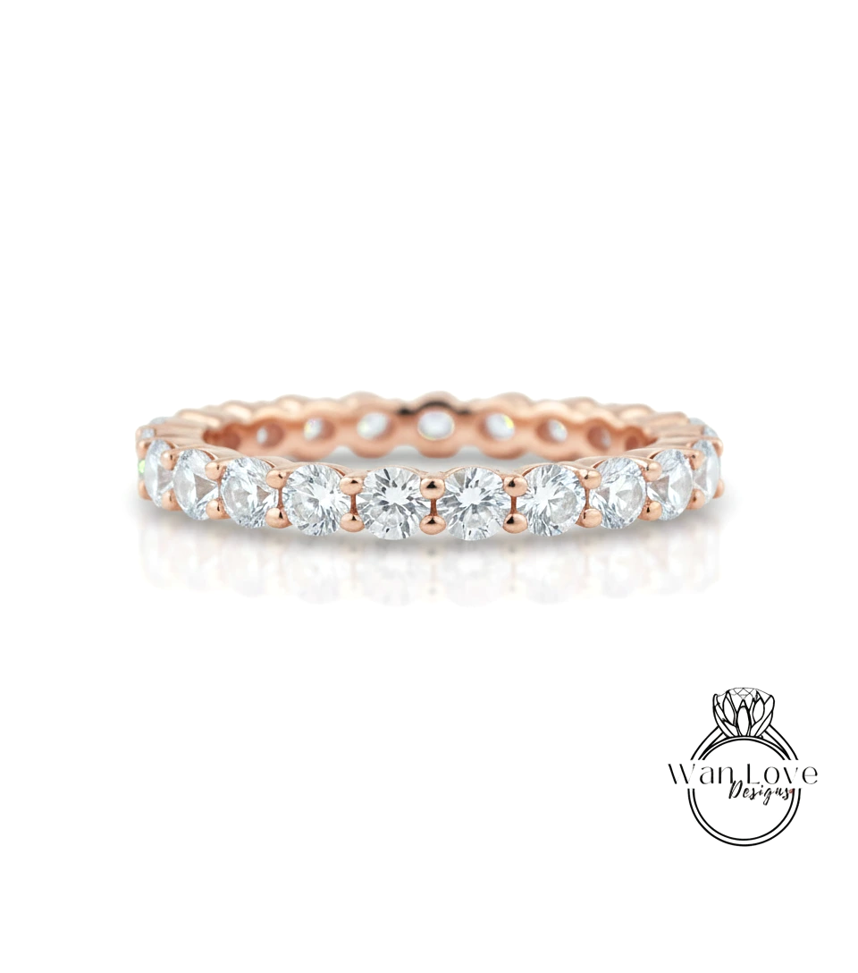 A rose gold band with a row of clear diamonds set in it.
