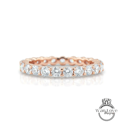 A rose gold band with a row of clear diamonds set in it.