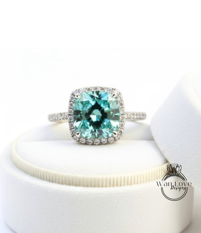 A stunning ring featuring a large, square-cut blue gemstone surrounded by a halo of smaller diamonds, set in a silver band.