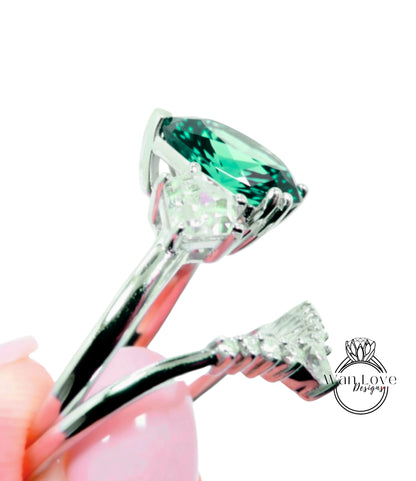 A close-up view of a silver ring with a large, green gemstone set in it, held in a hand against a white background.