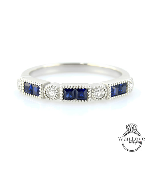 A silver ring with a row of blue gemstones, including diamonds, set in a decorative pattern.