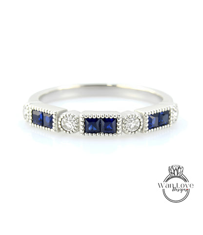 A silver ring with a row of blue gemstones, including diamonds, set in a decorative pattern.