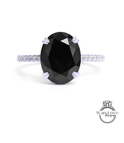 A large oval-shaped black diamond engagement ring with a silver band and small diamonds around the edges.