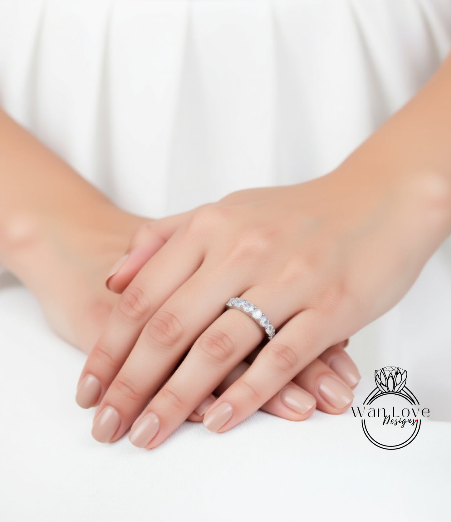 A close-up image of a person's hands wearing a diamond ring on the ring finger.