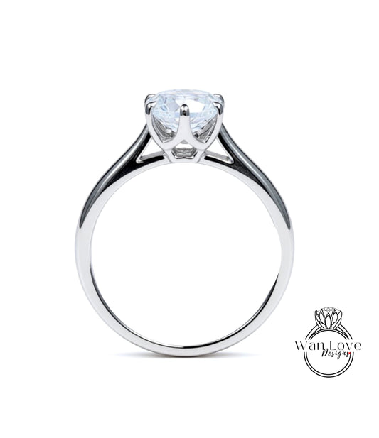 A silver engagement ring with a large, clear gemstone set in the center of the band.