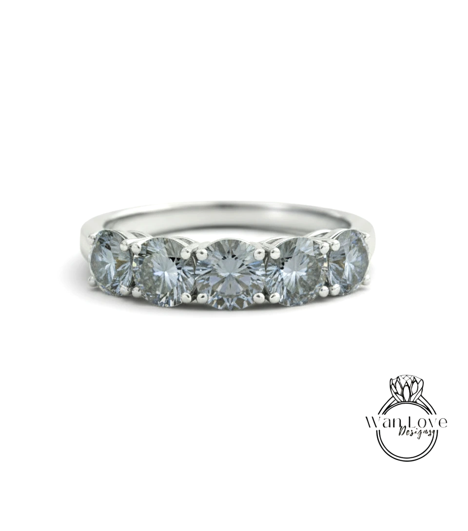 A silver ring with a row of five large, clear diamonds set in the band.