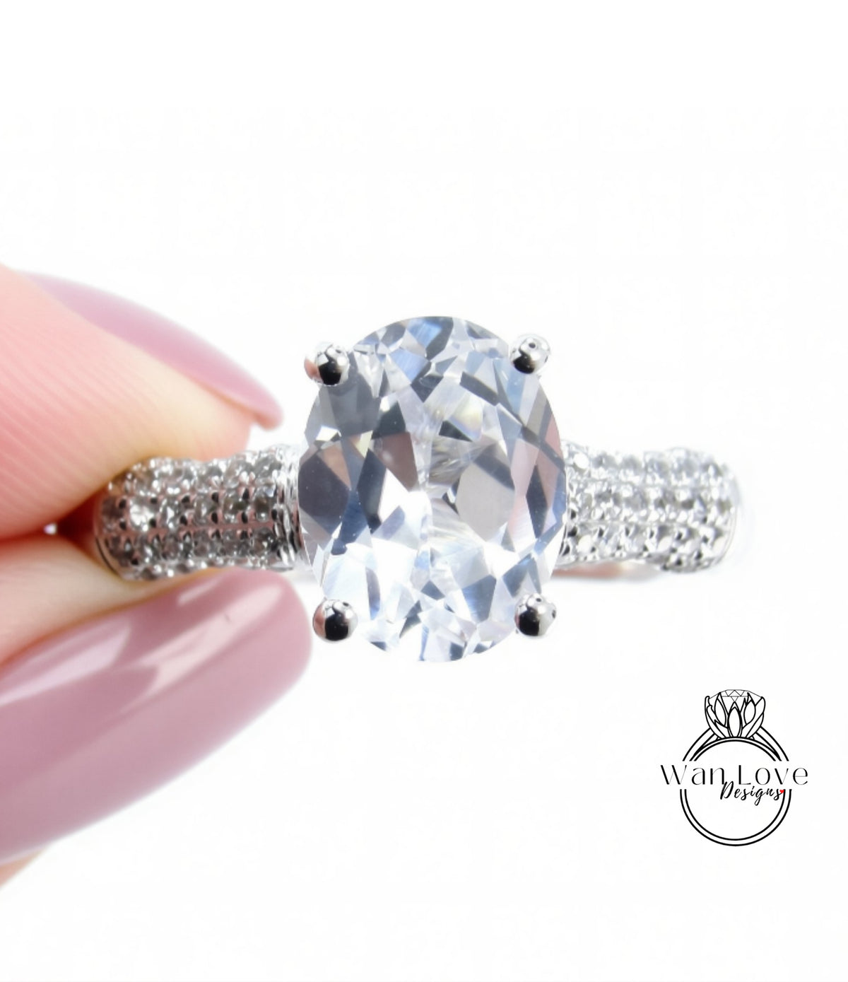 A close-up image of a person's hand holding a diamond ring with a large oval-shaped gemstone.