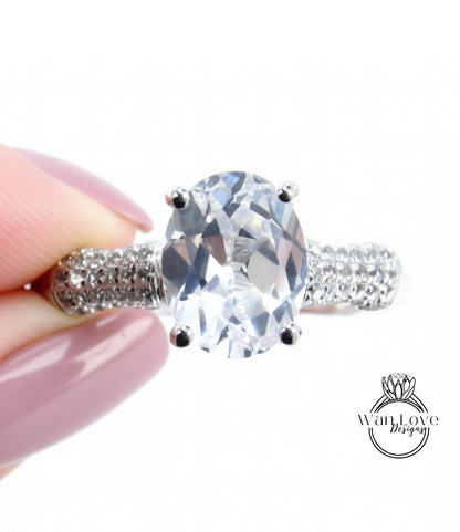 A close-up image of a person's hand holding a diamond ring with a large oval-shaped gemstone.