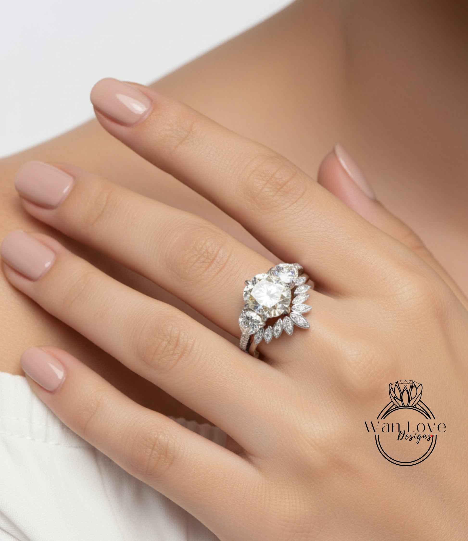 A close-up of a person's hand wearing a diamond engagement ring with a large central diamond surrounded by smaller diamonds on either side.