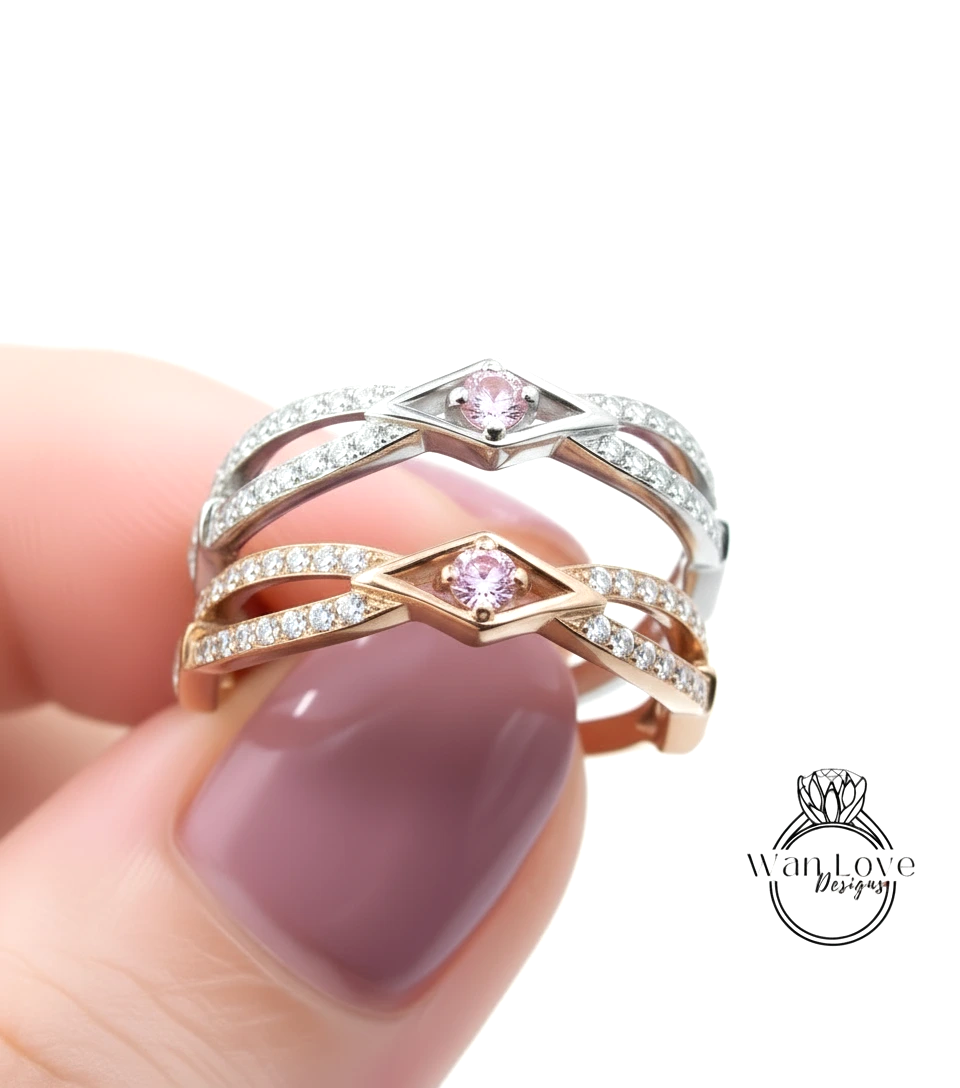 A close-up of a person's hand holding a ring with a pink gemstone in the center.