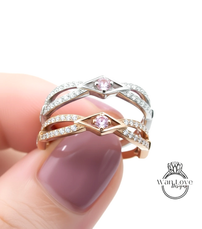 A close-up of a person's hand holding a ring with a pink gemstone in the center.