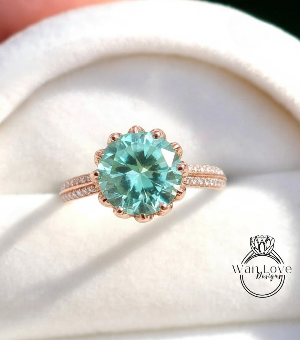 A close-up image of a rose gold ring with a large, round aquamarine gemstone set in the center.