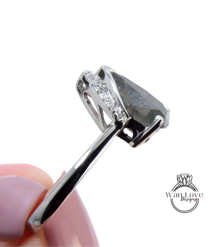 A close-up view of a silver ring with a large, irregularly shaped gemstone, possibly a diamond, set in the center.