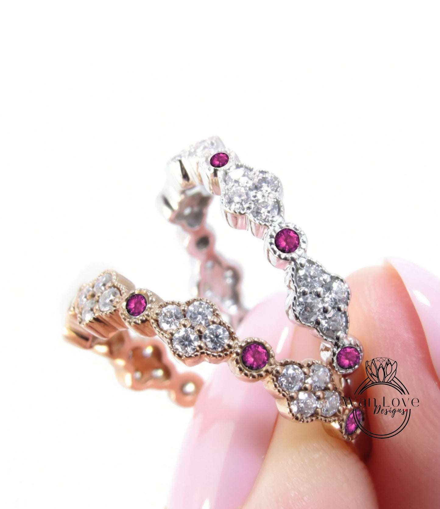 A close-up of a person's hand holding a ring with a combination of gold and silver materials, adorned with small diamonds and pink gemstones.