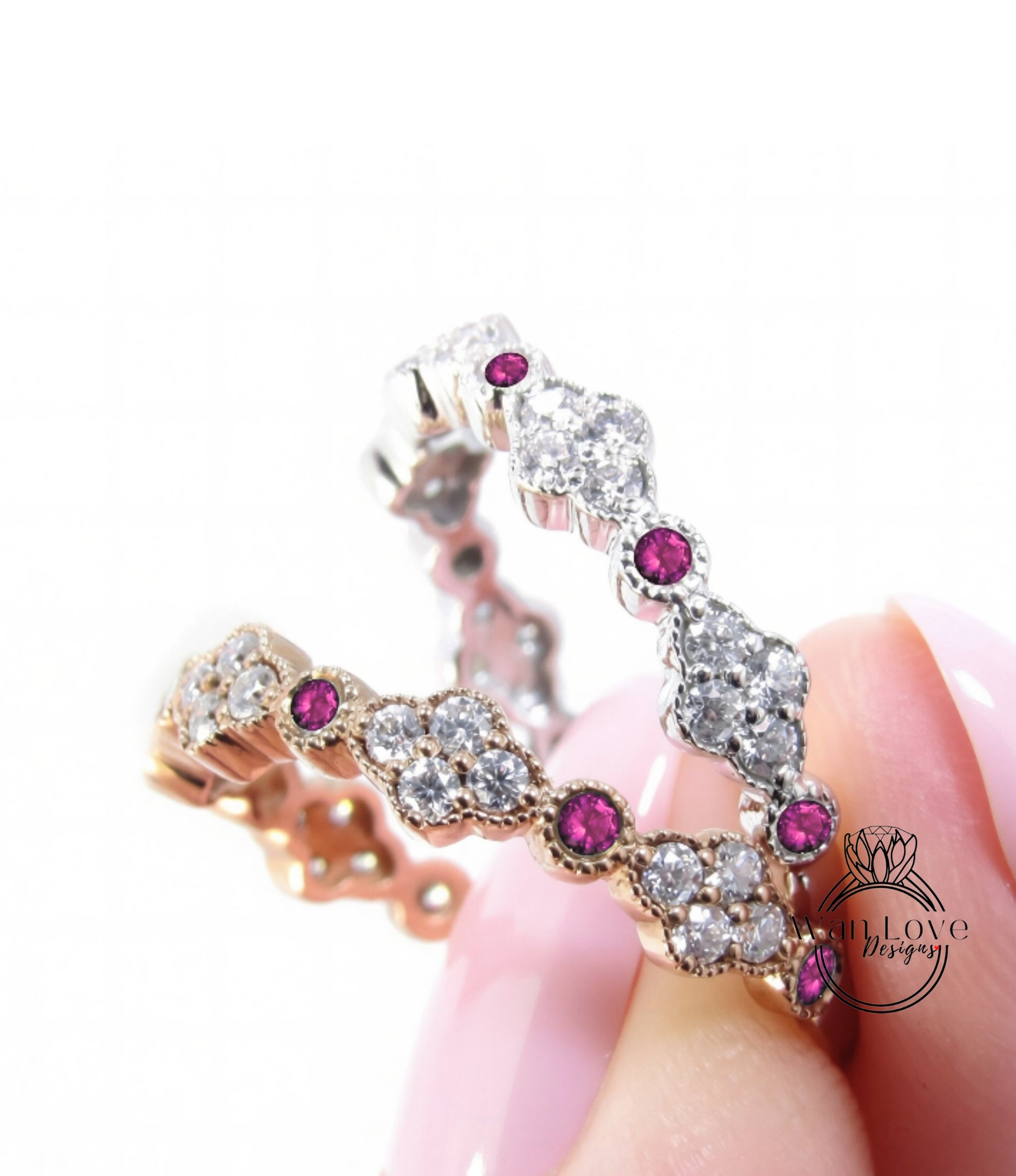 A close-up of a person's hand holding a ring with a combination of gold and silver materials, adorned with small diamonds and pink gemstones.