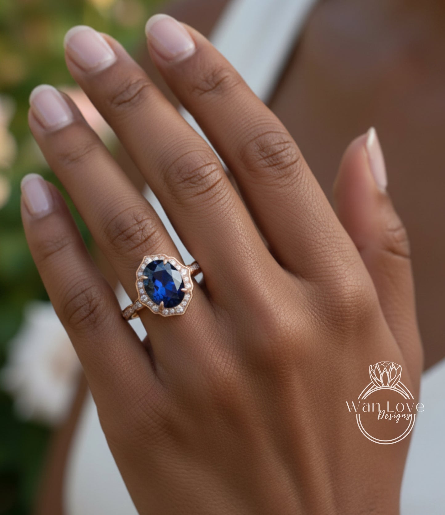 A close-up of a person's hand wearing a gold ring with a large blue gemstone, likely a sapphire.