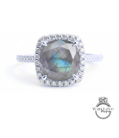 A silver ring with a large, blue-green gemstone at the center, surrounded by a halo of smaller diamonds.