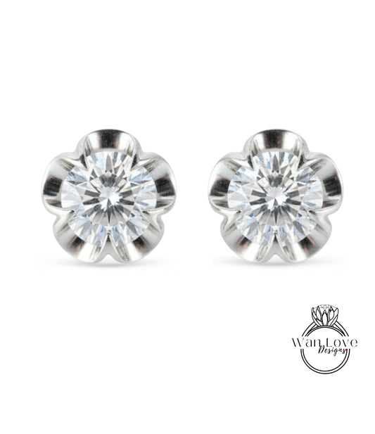 A pair of elegant silver earrings with a large, clear gemstone set in a flower-shaped design.