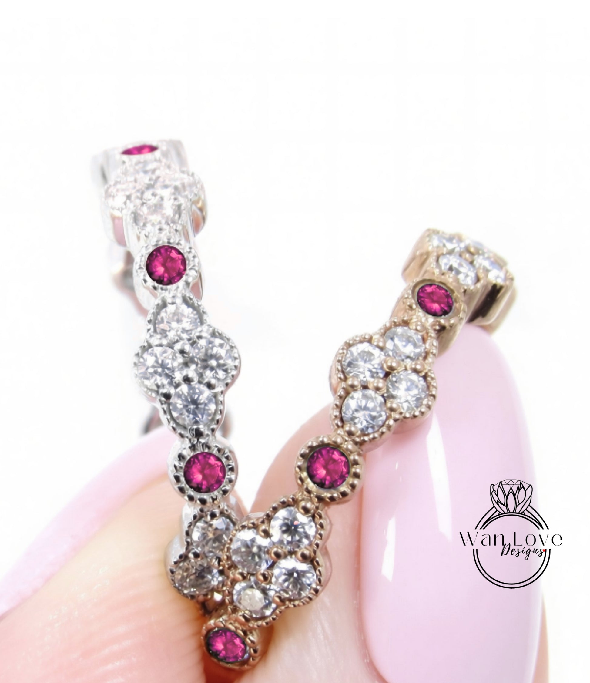 A close-up image of a person's hand holding a pair of elegant earrings adorned with sparkling diamonds and vibrant red gemstones.
