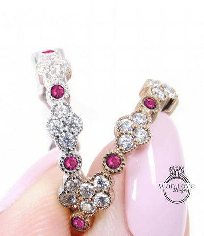 A close-up image of a person's hand holding a pair of elegant earrings adorned with sparkling diamonds and vibrant red gemstones.