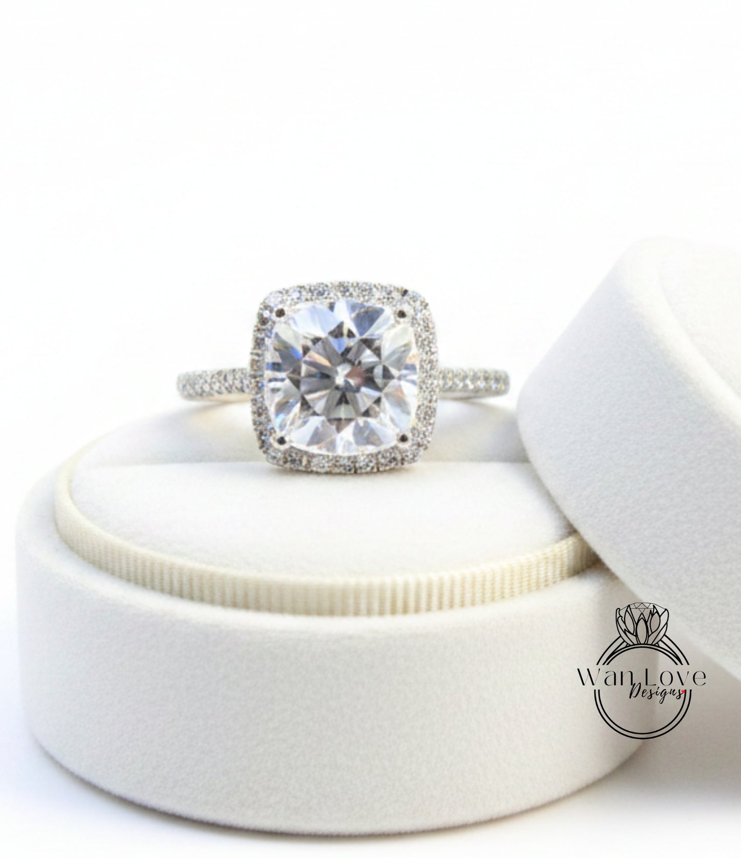 A large, clear diamond engagement ring with a halo of smaller diamonds around the center stone, displayed in a white jewelry box.
