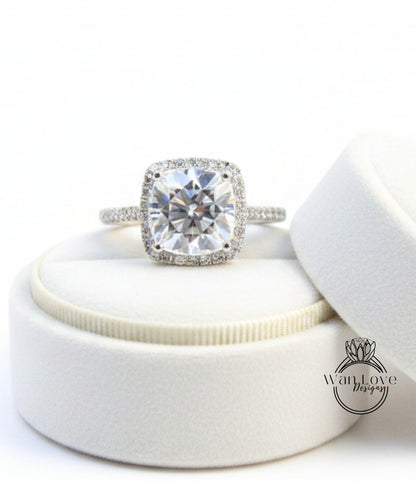 A large, clear diamond engagement ring with a halo of smaller diamonds around the center stone, displayed in a white jewelry box.