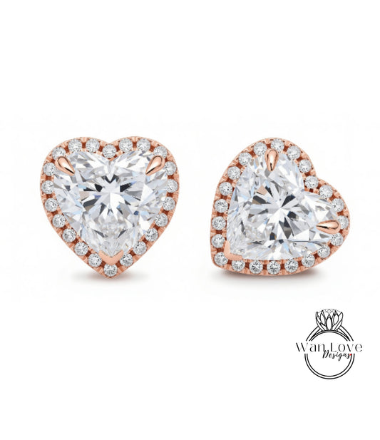 two heart-shaped earrings with large, clear gemstones set in a rose gold frame.