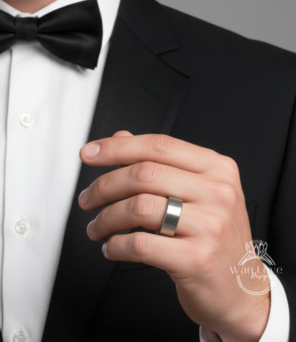 A close-up of a person's hand wearing a silver ring, with a black bow tie and a black suit jacket.