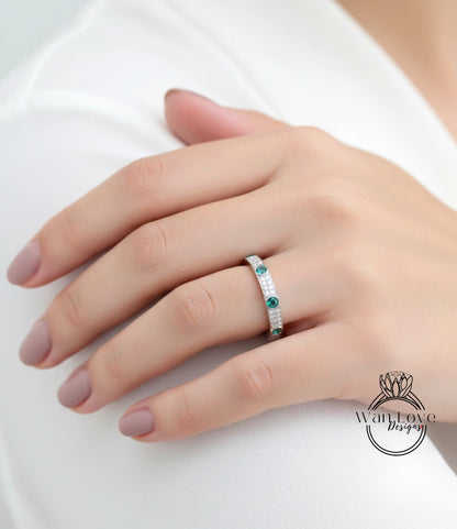 A close-up of a person's hand wearing a ring with a row of small diamonds set in the center.