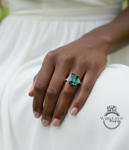 A close-up of a person's hand wearing a large, green gemstone ring.