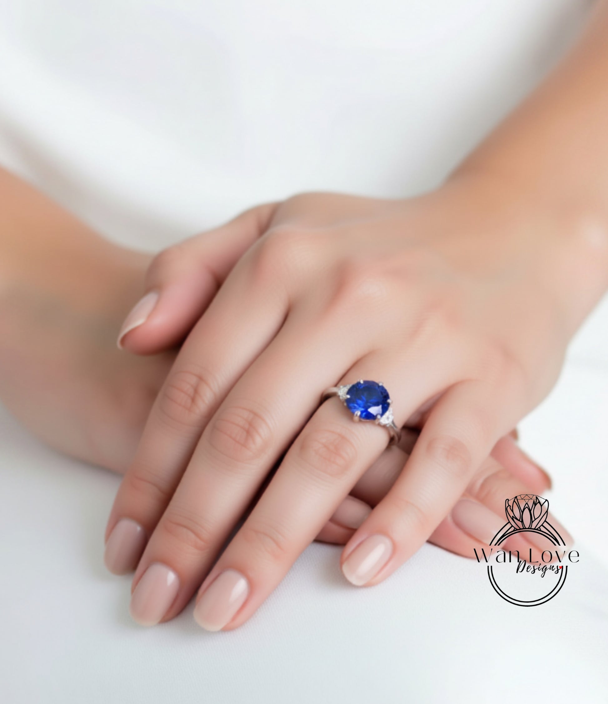 A close-up image of a person's hand wearing a ring with a large blue gemstone.
