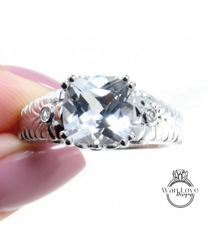 A close-up image of a person's hand holding a silver ring with a large, clear gemstone.
