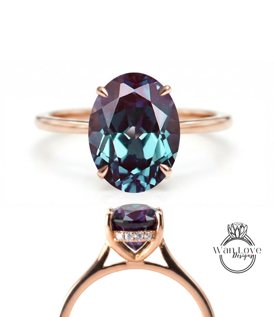 a gold ring with a large oval-shaped gemstone, which appears to be a deep blue color. The ring is set with a smaller gemstone, possibly a diamond, and is displayed in two different views.