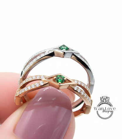 A close-up of a person's hand holding a ring with a diamond-encrusted band and a green gemstone.
