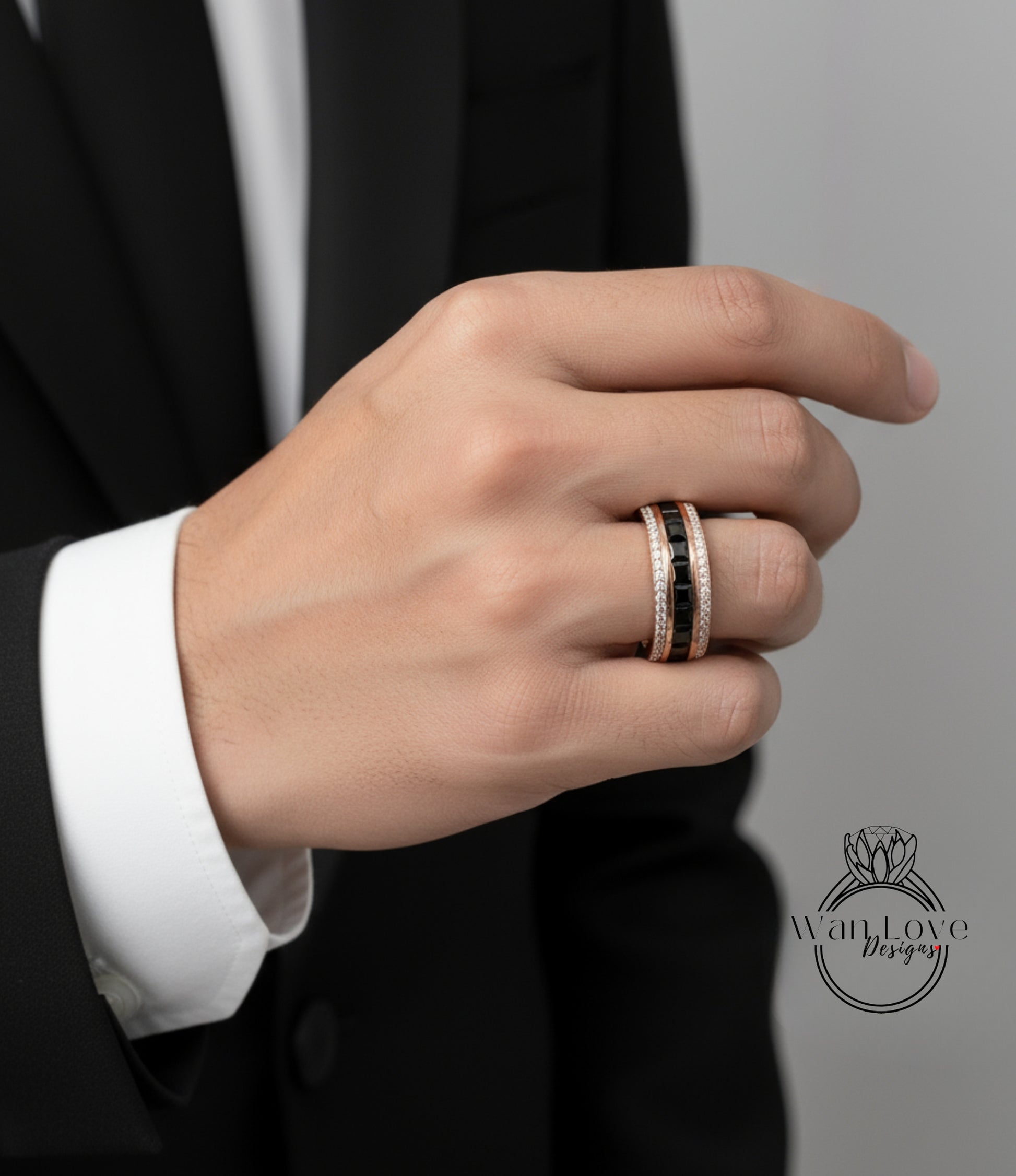 A close-up of a person's hand wearing a gold ring with a black gemstone band.