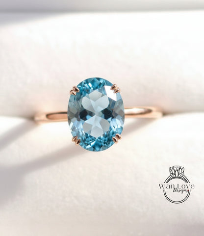 A close-up image of a gold ring with a large oval-shaped blue gemstone, likely an aquamarine, set in the center of the band.