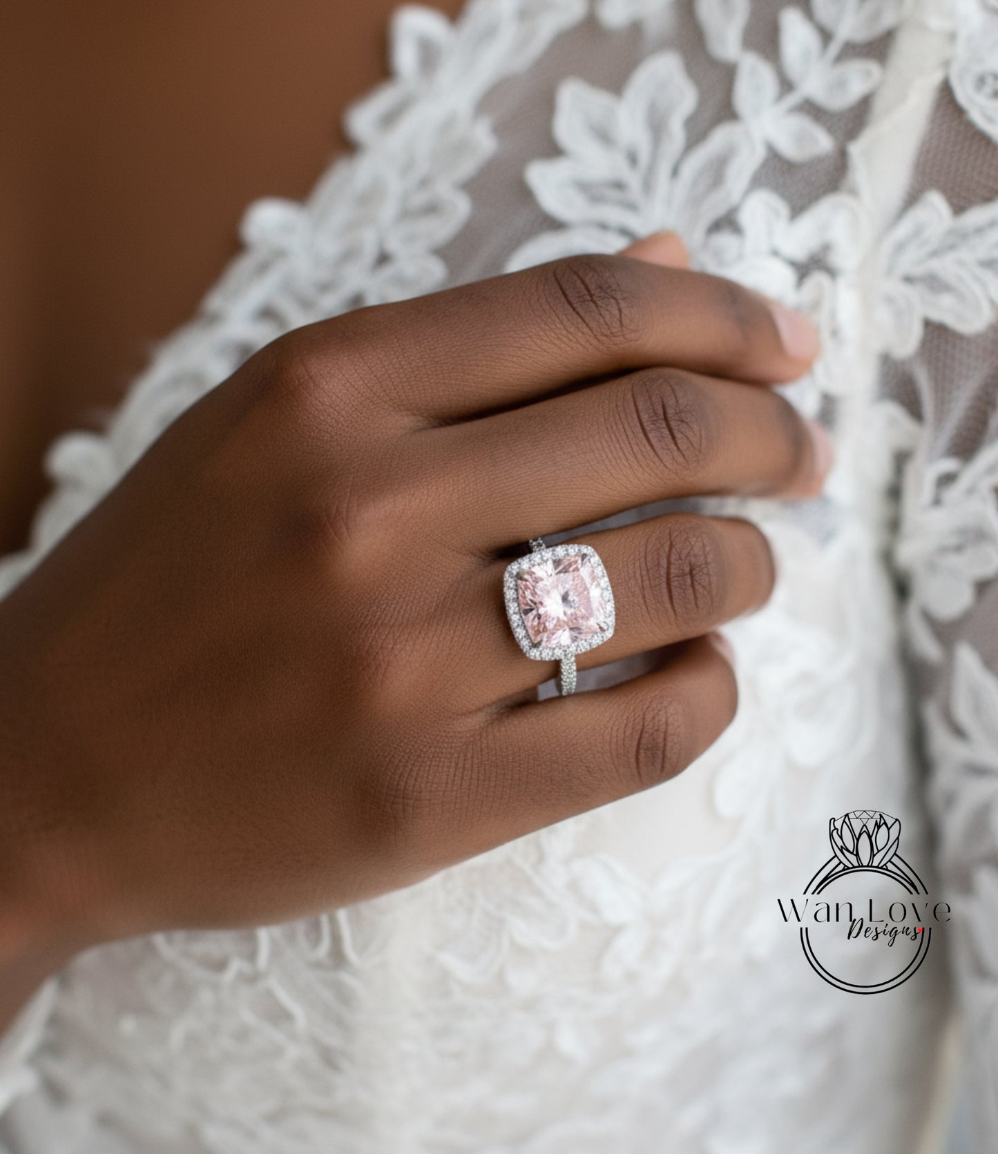 A close-up of a hand wearing a large, pink diamond ring on the ring finger.
