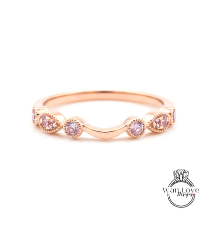 A rose gold ring with a curved band and small pink gemstones.
