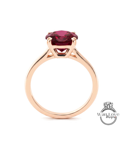 A gold ring with a large, deep red gemstone set in the center.