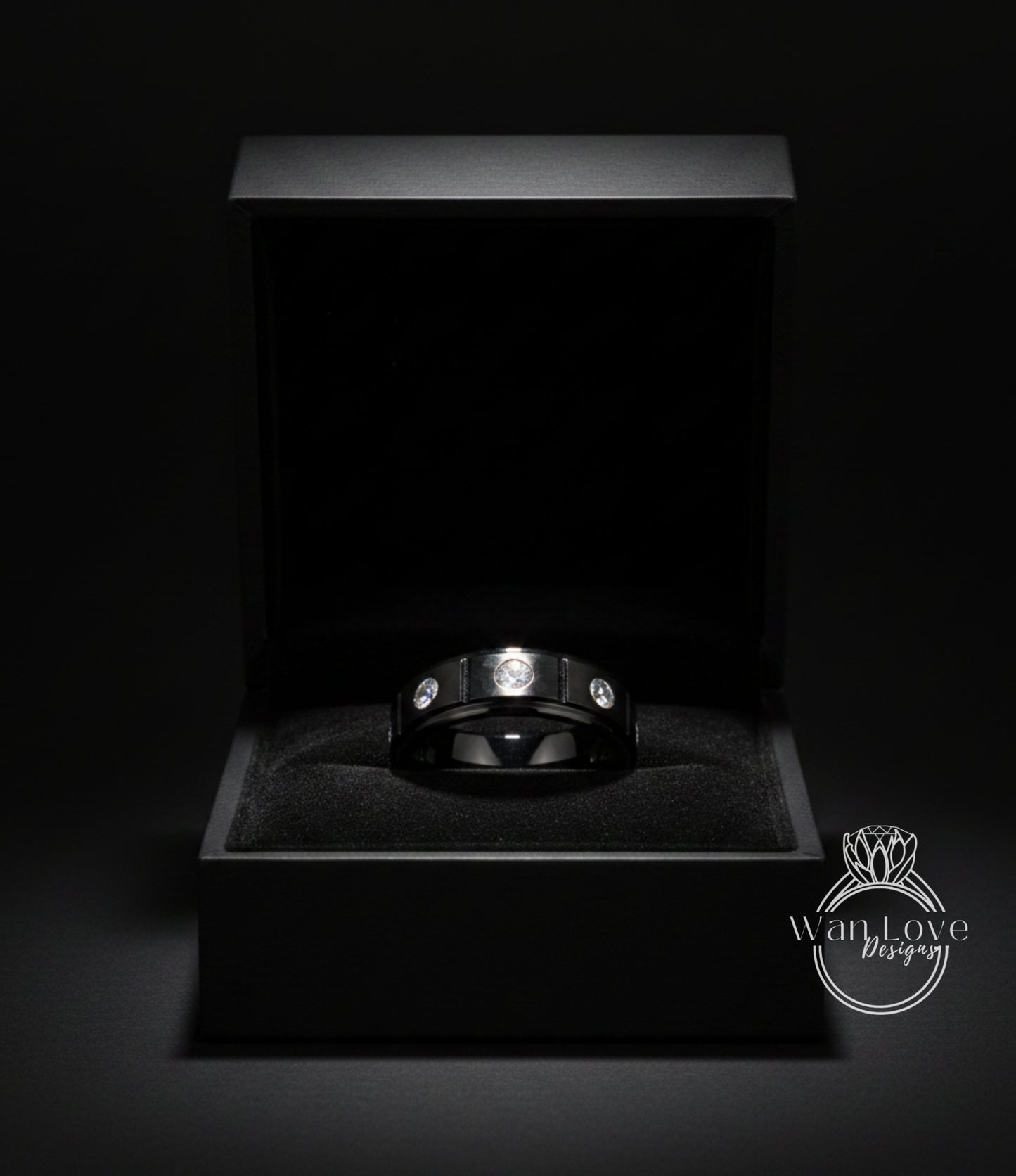 A black jewelry box containing a silver ring with three diamonds.