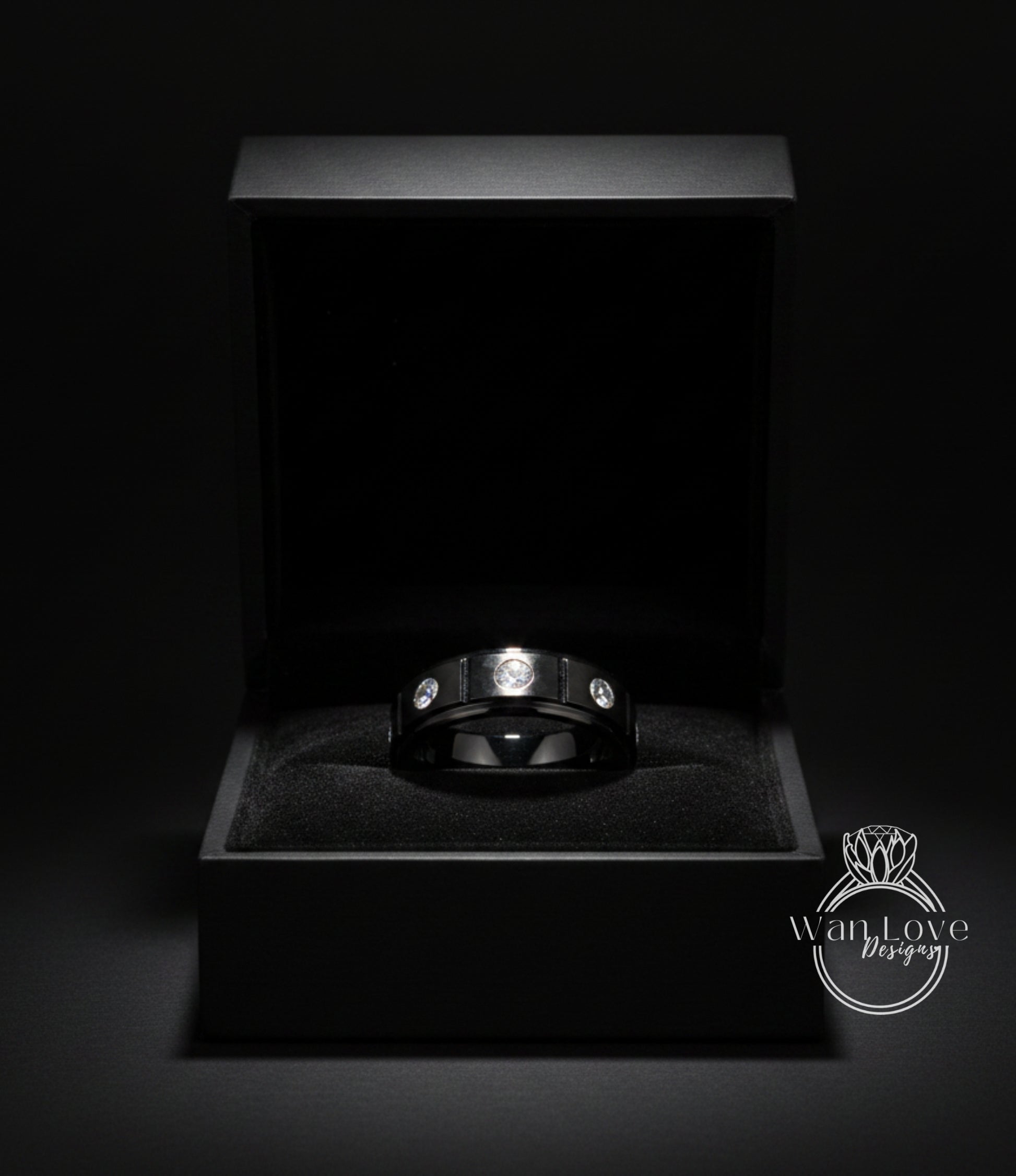A black jewelry box containing a silver ring with three diamonds.