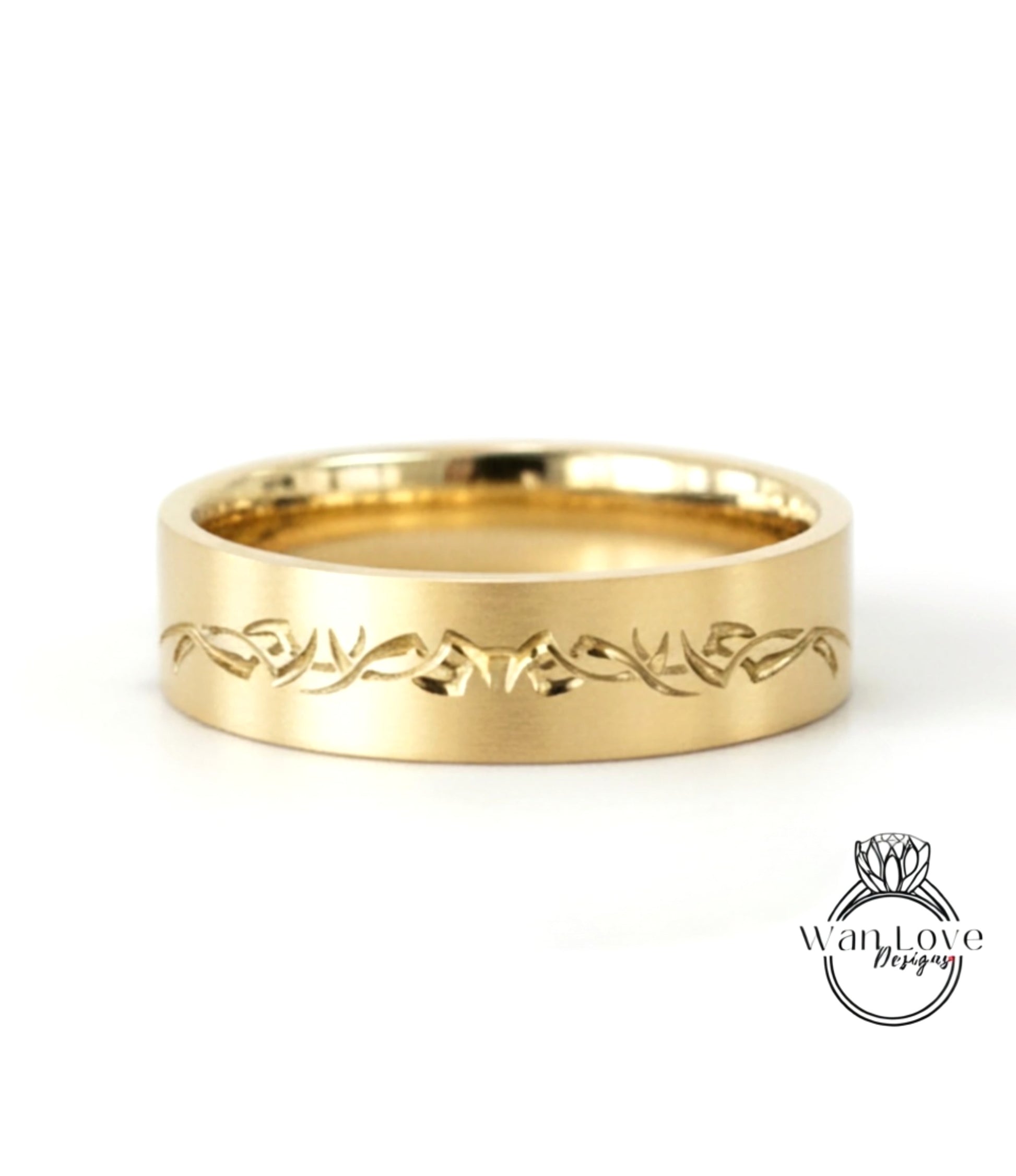 A gold-colored ring with a decorative engraved design on the band.