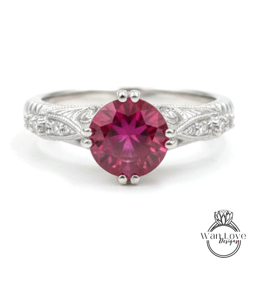 A close-up image of a silver ring with a large, deep red gemstone at the center.