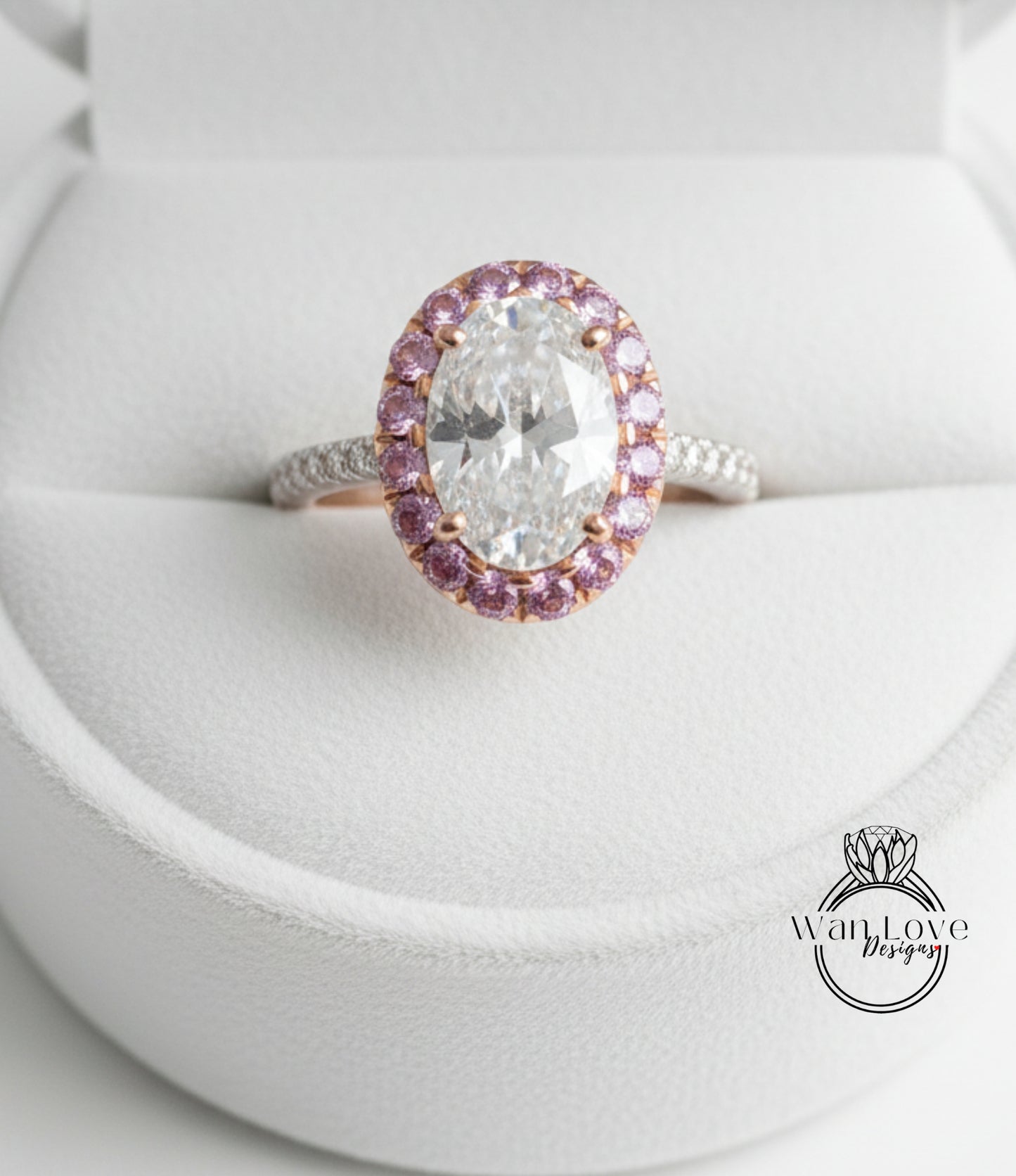 A close-up image of a diamond engagement ring with a large oval-shaped diamond surrounded by a halo of smaller diamonds and pink gemstones.