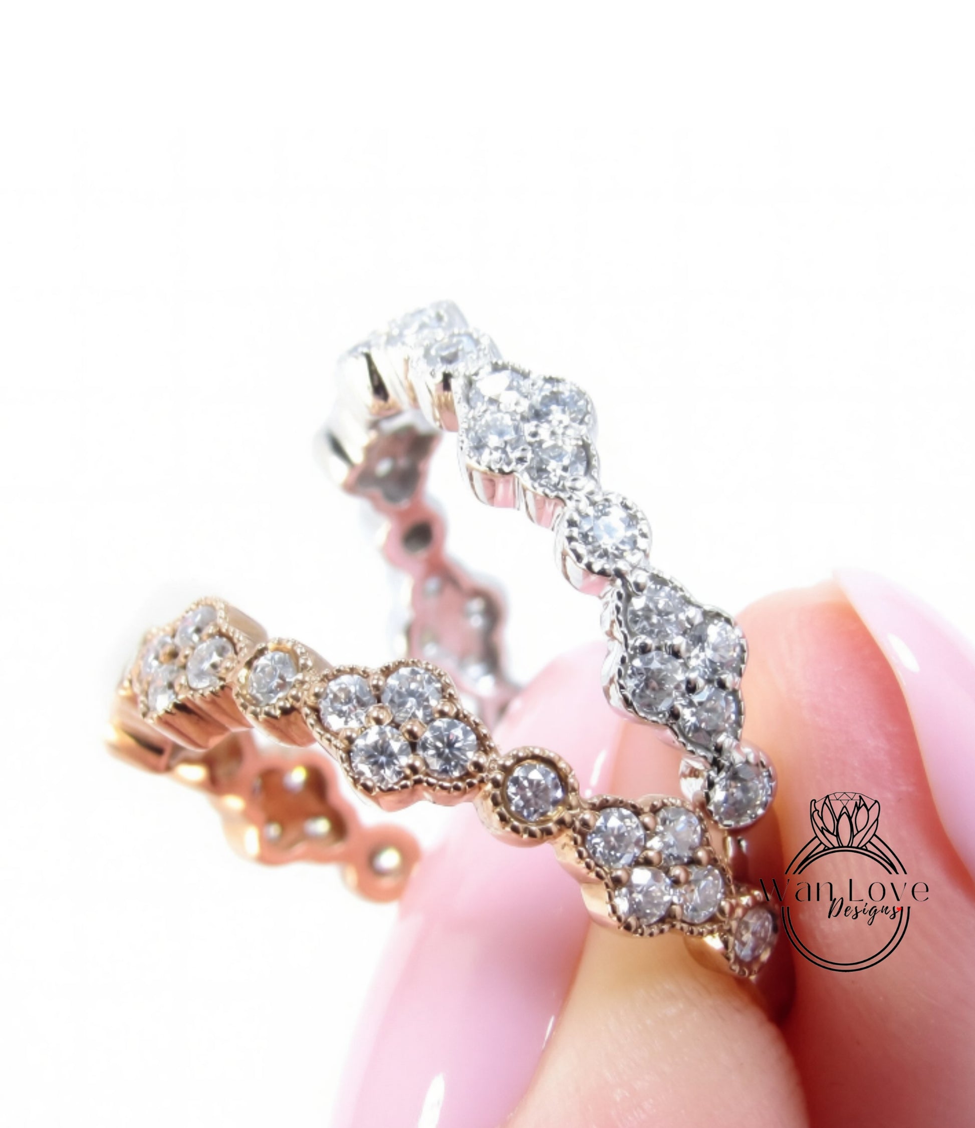 A close-up of a person's hand holding a ring with a row of small diamonds set in a gold band.