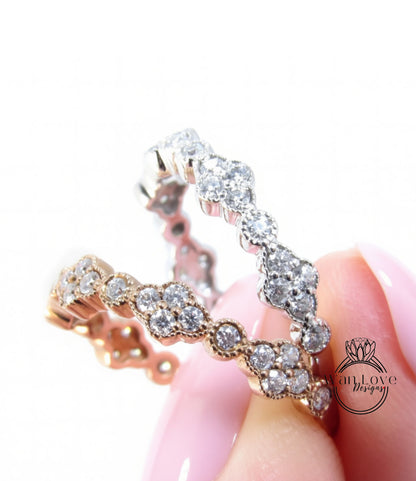 A close-up of a person's hand holding a ring with a row of small diamonds set in a gold band.