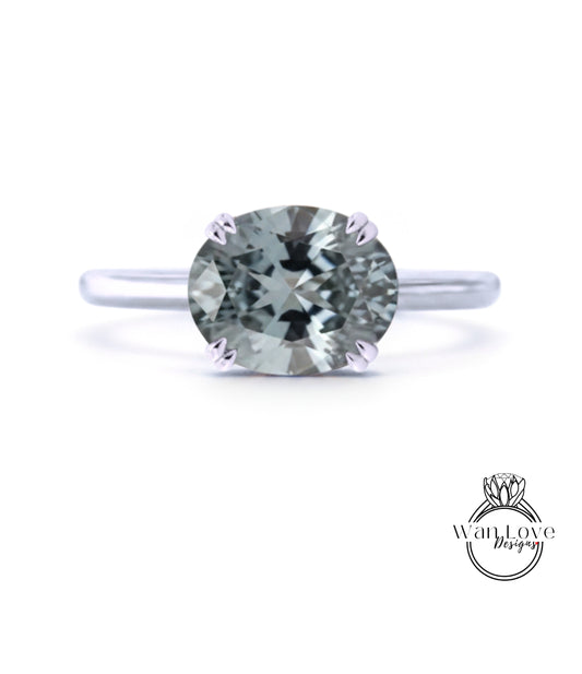 A silver ring with a large, round, gray diamond as the centerpiece.